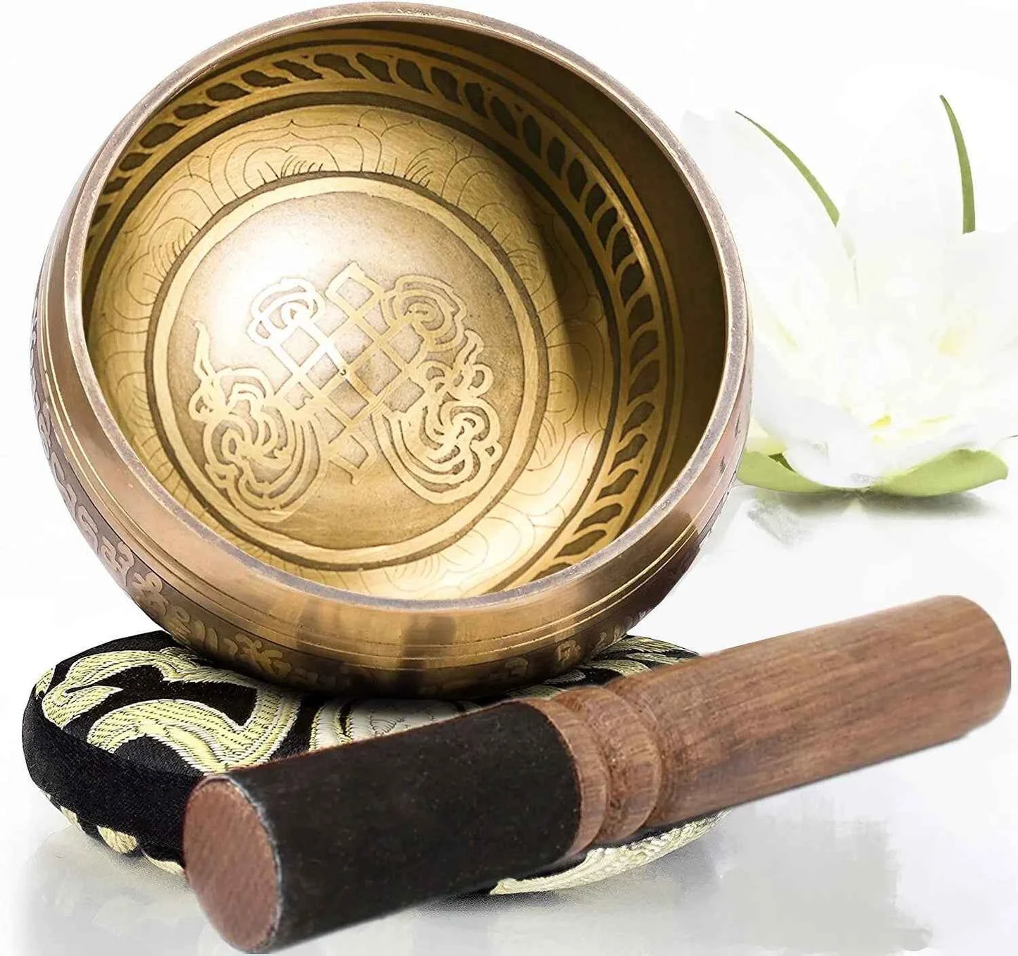 Bol chantant doré décoré avec des motifs, accompagné d'un maillet en bois sur un coussin