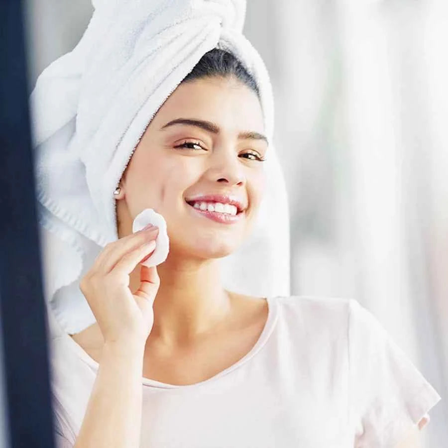 Femme souriante utilisant des disques démaquillants réutilisables après un nettoyage du visage