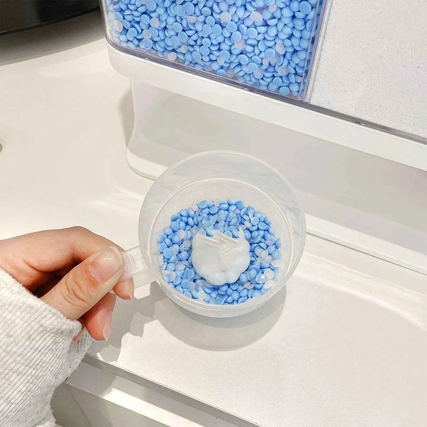 Distributeur de lessive en poudre rempli de perles bleues avec une cuillère pour dosage facile