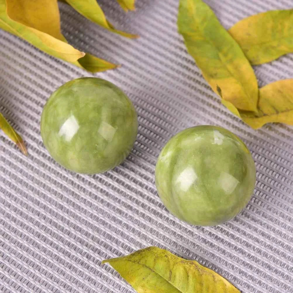 Boules de jade bien-être vertes posées sur une surface avec des feuilles jaunes pour un effet apaisant