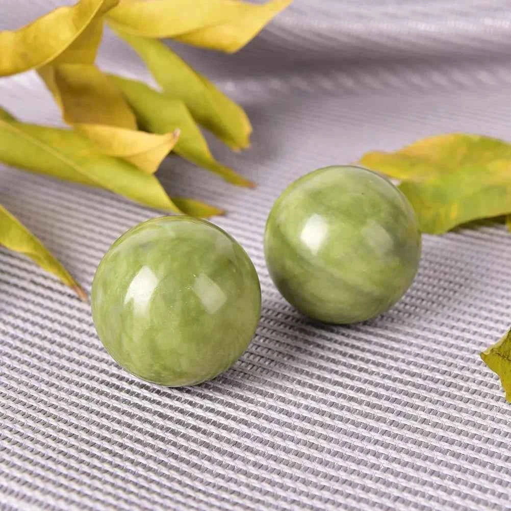 Boules de jade bien-être sur une surface grise avec des feuilles en arrière-plan
