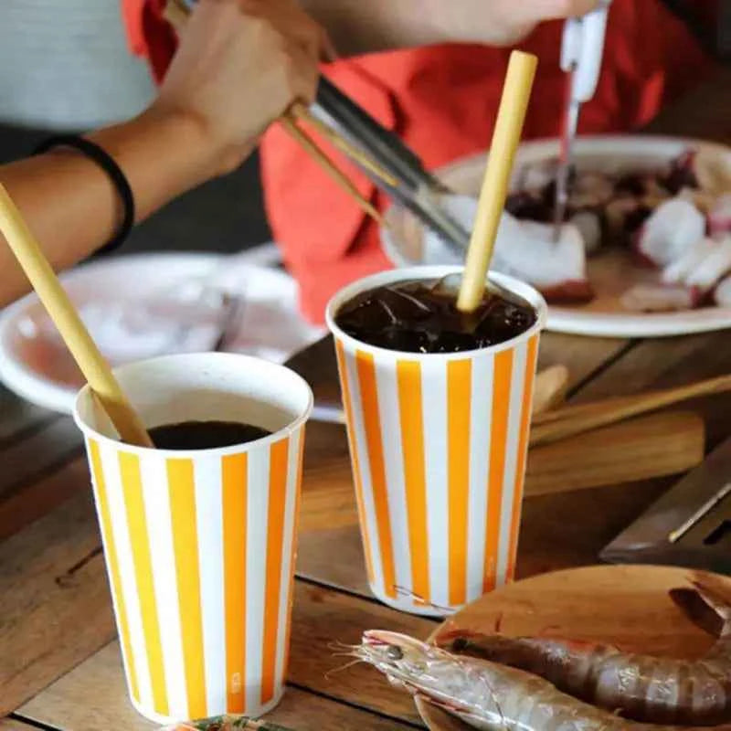 Pailles en bambou écologiques utilisées avec des boissons dans des gobelets en papier