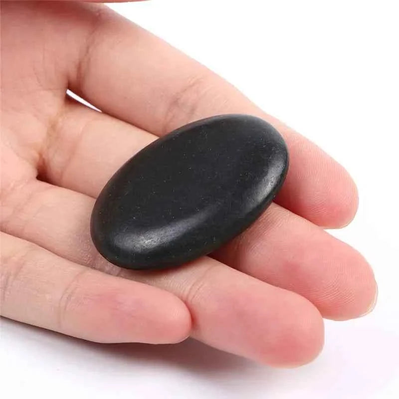 Pierre de massage énergétique noire tenue dans une main pour les soins de bien-être