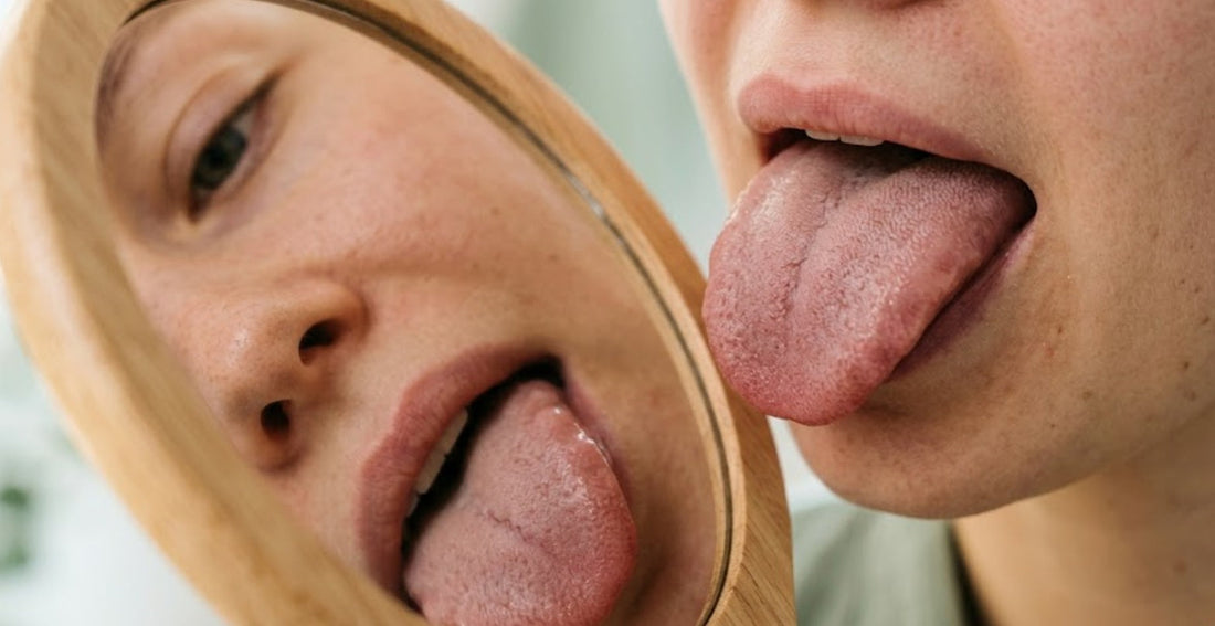 Jeune femme observant la couleur et l'aspect de sa langue dans un miroir pour évaluer son métabolisme et son microbiote digestif