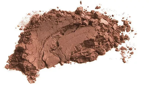 Zoom sur de l'argile rouge en poudre étalé sur une surface blanche. L'argile rouge est douce et reminéralisante, idéale pour des peaux sèches, pour le visage ou les cheveux, voir même en usage interne.